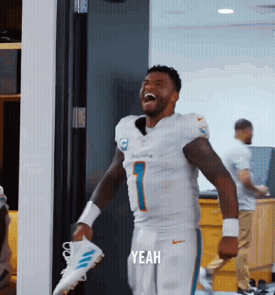 Man In Miami Dolphins Uniform Laughing Holding Shoes GIF