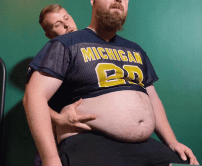 Man In Michigan Jersey Holding Another Man's Stomach GIF