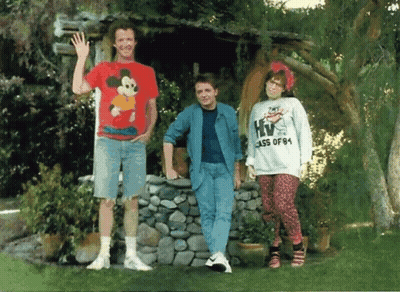 Man In Mickey Mouse Shirt Next To Woman In HIV Class Of '84 Sweatshirt GIF