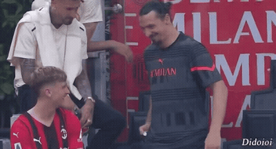 Man In Milan Shirt Talking To Red Shirt Man GIF