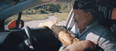 Man In Military Hat Driving Car Holding Bread GIF