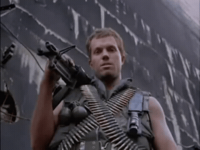 Man In Military Uniform Holding Gun In Front Of Ship GIF