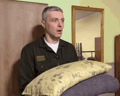 Man In Military Uniform Holding Pillow GIF