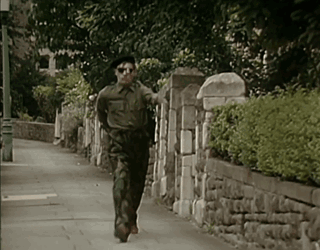 Man in Military Uniform Running Down Street