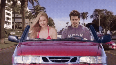 Man In Moon Shirt Driving Red Car With Woman In Bikini GIF
