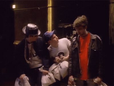 Man In NASA Shirt Talking To Two Men Holding Money Bags GIF