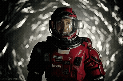 Man In NASA Space Suit Smiling In Dark Room GIF