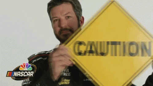 Man In NASCAR Jacket Holding Yellow Caution Sign GIF