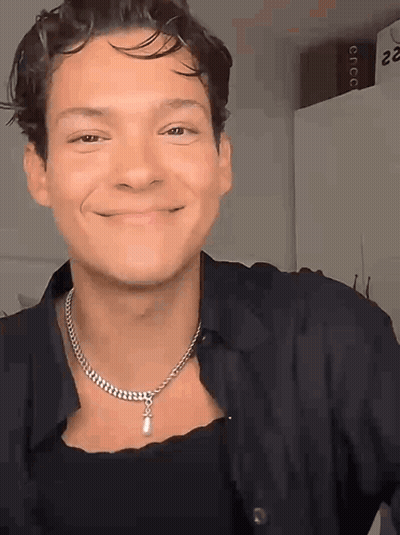 Man In Necklace And Black Shirt Smiling GIF