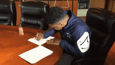 Man In Nike Jacket Writing At Conference Table GIF