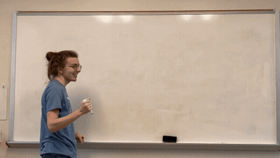 Man in Northwest Vista College Wildcats Shirt Writing on Whiteboard