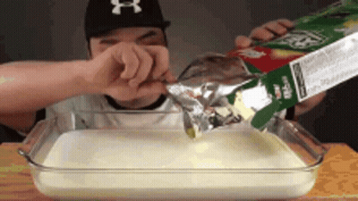 Man In NY Hat Pouring Milk Into Glass Dish GIF