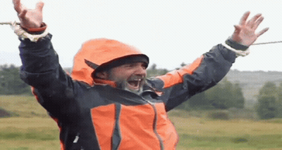 Man In Orange And Black Jacket Laughing Arms Up GIF