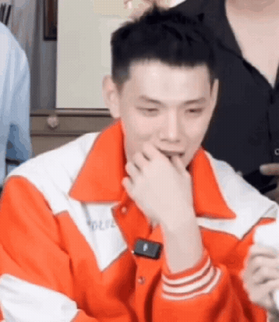 Man In Orange And White Jacket Sitting GIF