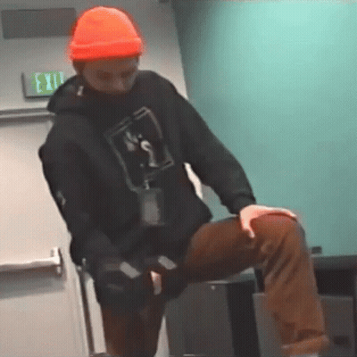 Man In Orange Hat And Black Hoodie Kneeling On Table GIF