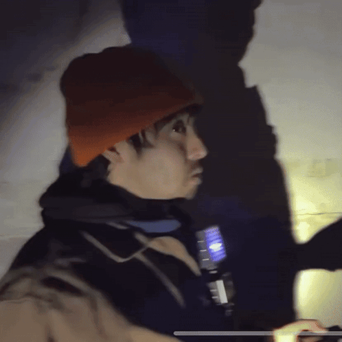 Man In Orange Hat And Black Jacket Holding Flashlight GIF