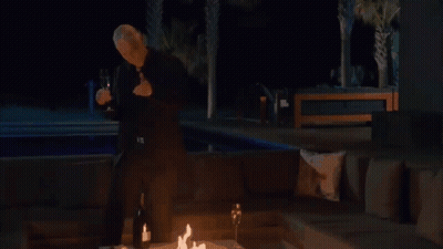 Man In Orange Hat Dancing In Front Of Gold And Silver Shine Painting GIF