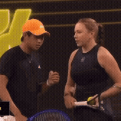 Man In Orange Hat Talking To Woman With Tennis Racquet GIF