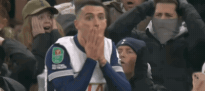 Man In Orange Hoodie And White Jacket Looking At Camera GIF