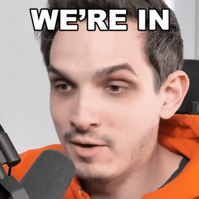 Man In Orange Hoodie Talking Into Microphone Saying We're In GIF