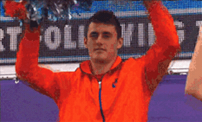 Man In Orange Jacket Holding Cheerleading Pom Pom GIF