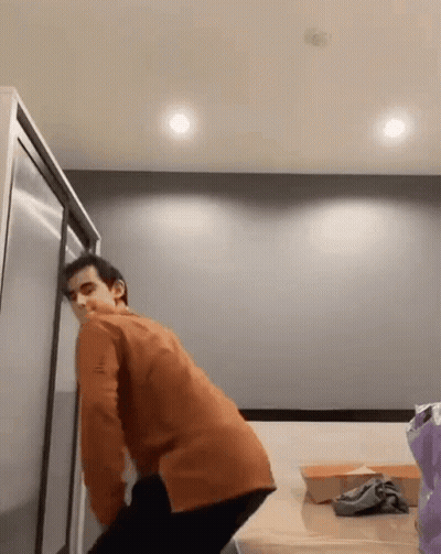 Man in Orange Jacket Standing in Front of Refrigerator