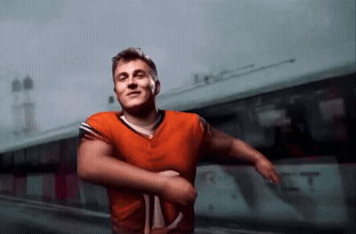Man In Orange Jersey In Front Of Bus Saying RT GIF