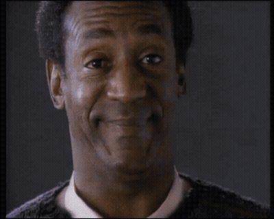 Man In Orange Playerz 69 Jacket Sitting At Table With Other Men GIF