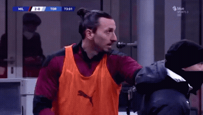Man In Orange Puma Vest At Microphone GIF