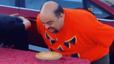 Man In Orange Shirt Blowing Out Pie GIF