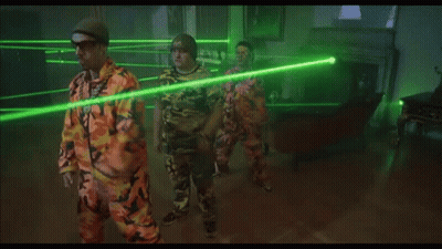 Man In Orange Shirt Facing Green Laser Beams GIF
