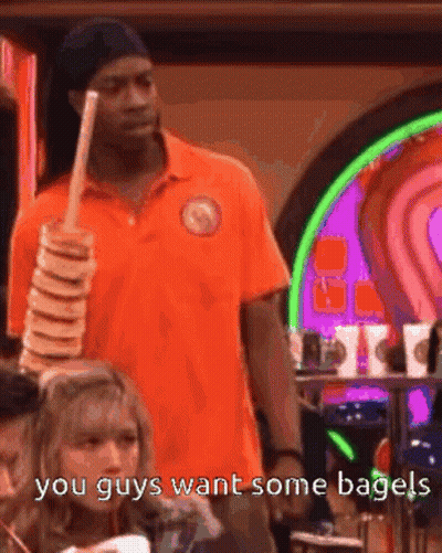 Man In Orange Shirt Holding Bagels Saying You Guys Want Some Bagels GIF