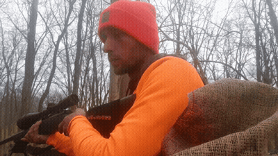 Man In Orange Shirt Holding Gun GIF