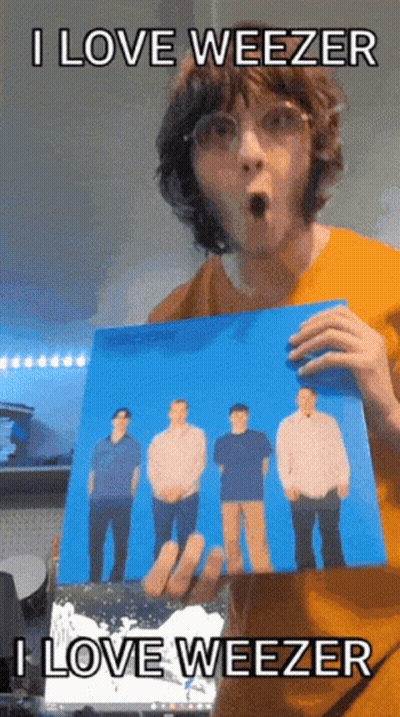 Man In Orange Shirt Holding Weezer Picture GIF