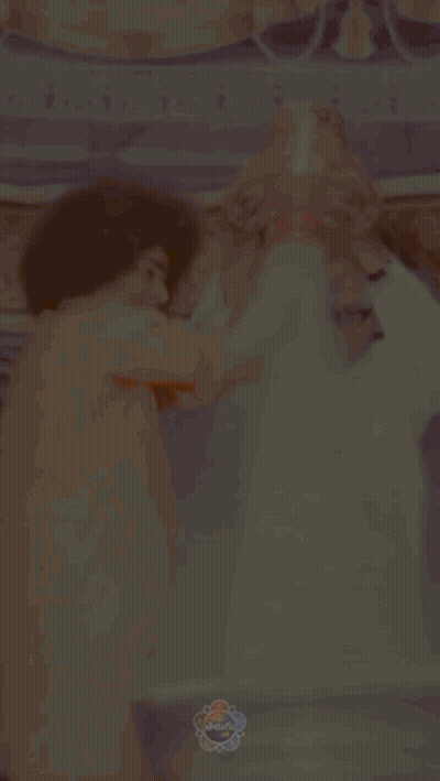Man In Orange Shirt Holds Bell Over Man In White Shirt GIF