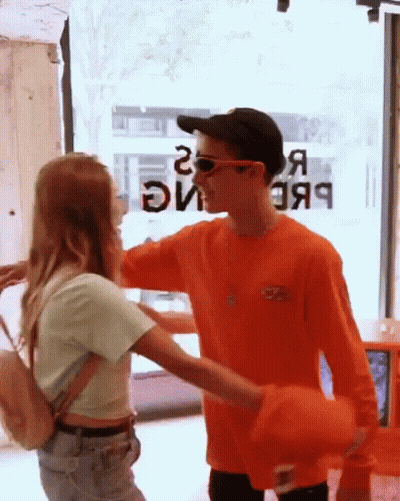 Man In Orange Shirt Hugging Girl In Front Of Window Saying Я GIF