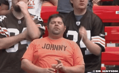 Man In Orange Shirt Johnny Sitting In Stadium GIF
