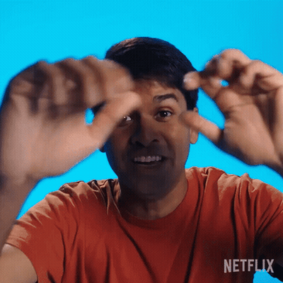 Man In Orange Shirt Making Funny Face In Front Of Netflix Background GIF