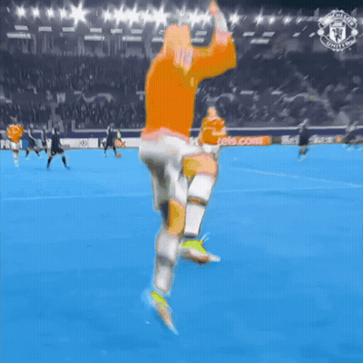 Man In Orange Shirt Running On Soccer Field With Manchester United Logo GIF