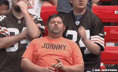 Man In Orange Shirt Saying Johnny Sitting In Stadium GIF