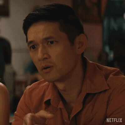 Man In Orange Shirt Sitting At Table With Netflix Logo GIF