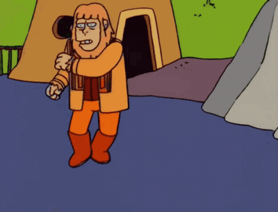 Man in Orange Standing in Front of Cave