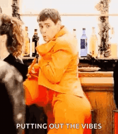 Man In Orange Suit Putting Out Vibes At Bar GIF