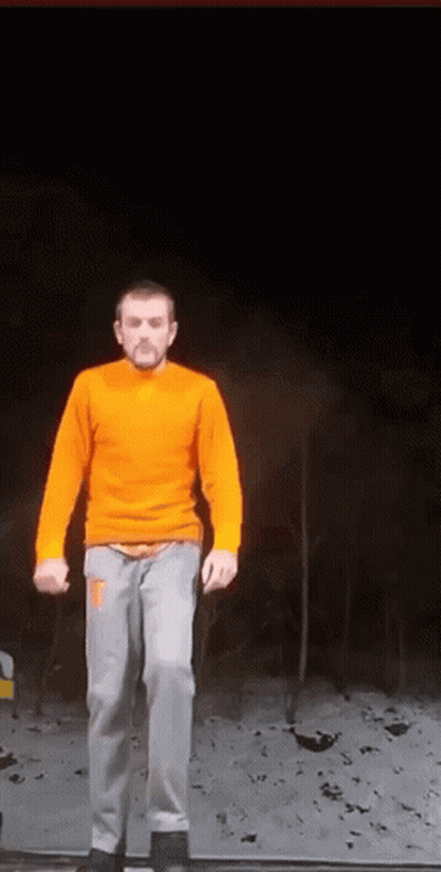 Man In Orange Sweater And Gray Pants On Ledge GIF
