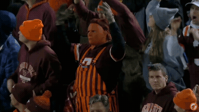 Man In Overalls And Mask In Crowd Wearing VT Hats GIF