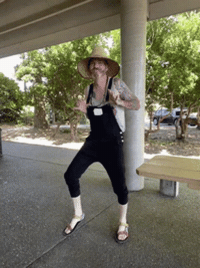 Man In Overalls And Straw Hat Standing On One Leg GIF