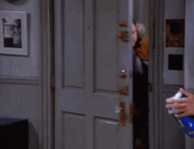Man In Parka Standing In Doorway While Person Sprays GIF