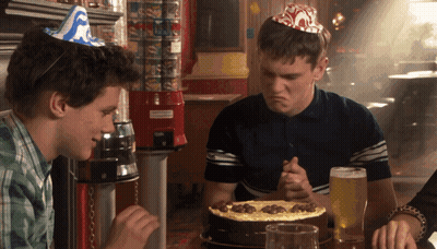 Man In Party Hat Sitting At Table With Pizza GIF