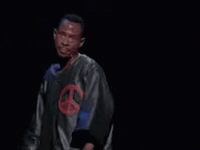 Man In Peace Sign Shirt Pointing At Word GIF