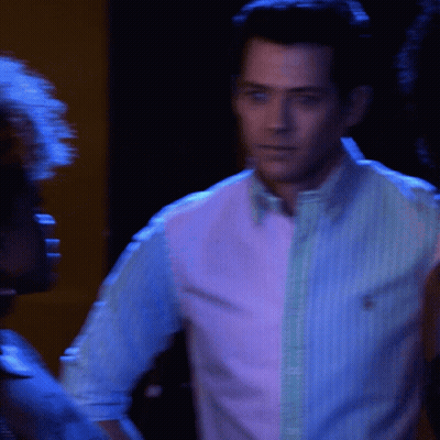 Man in Pink and Blue Striped Shirt in Dark Room
